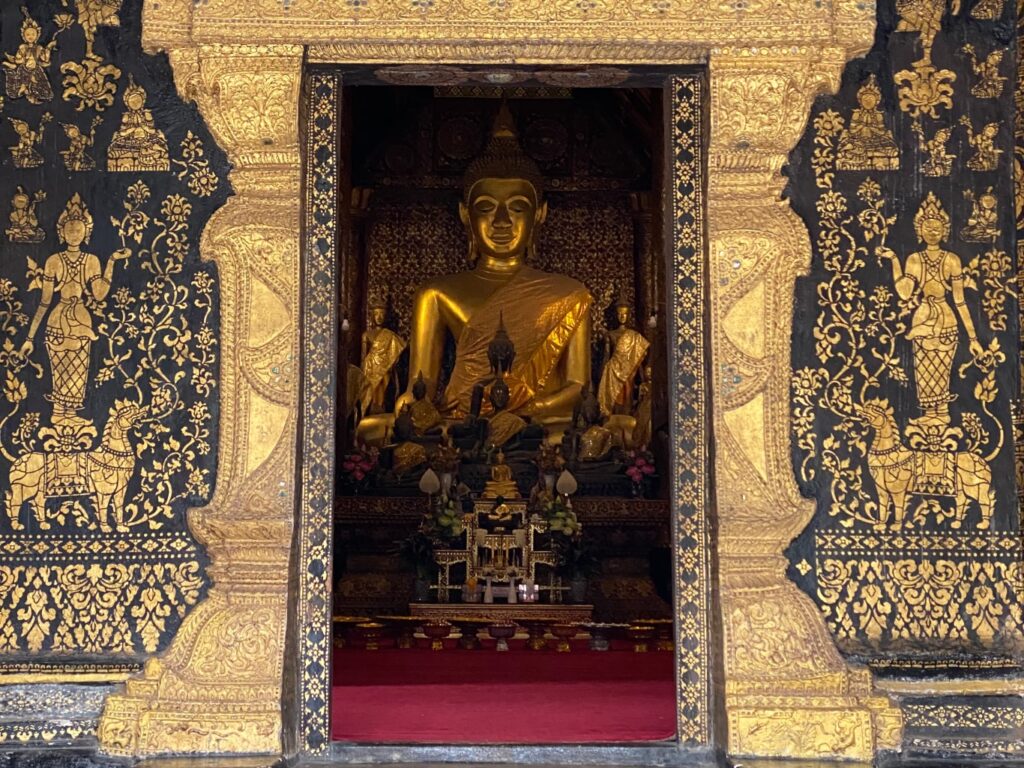 A temple in Luang Prabang with a buddha statue seen through the doorway