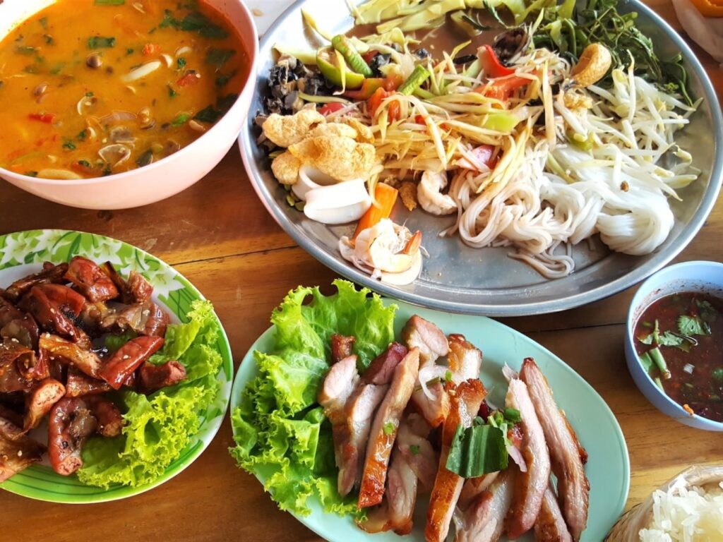 Plates of Lao food showing an assortment of fresh vegetables and meats