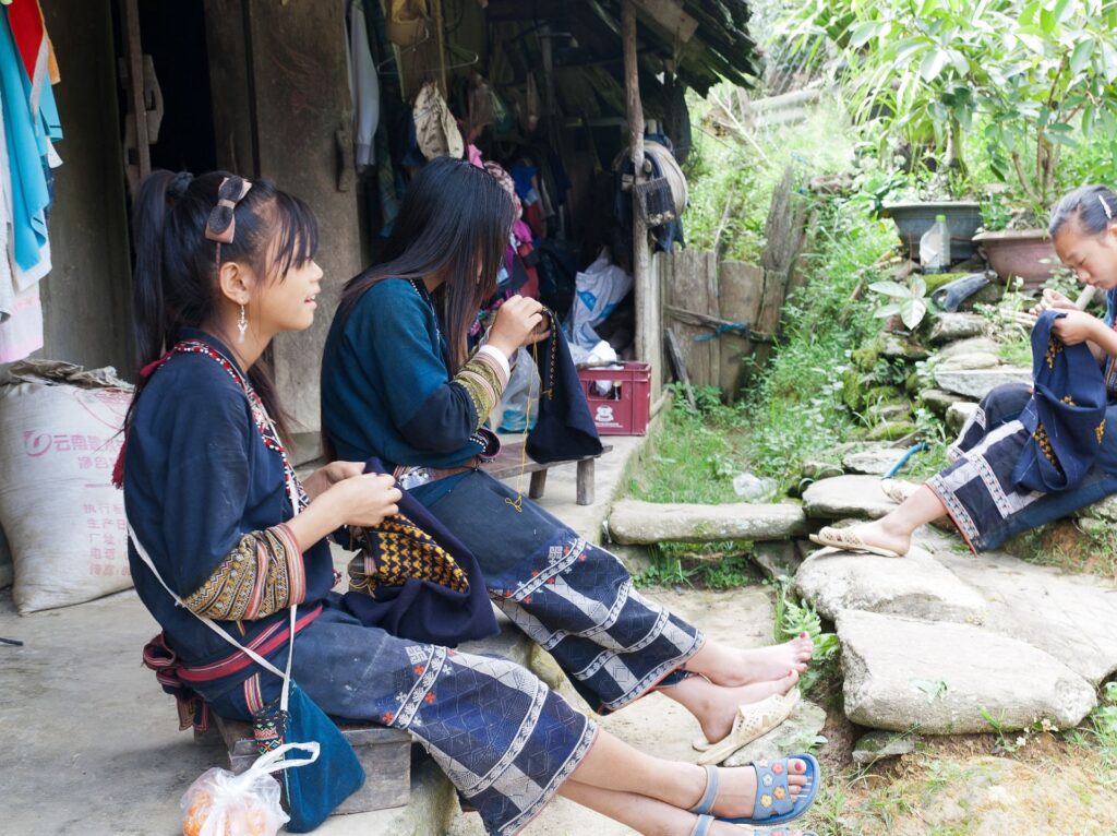 A group of Hmong women sitting and talking. Wearing traditional clothing